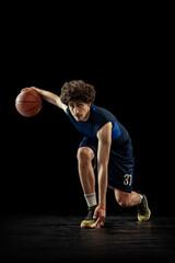 Professional basketball player in action and motion isolated on dark background. Concept of sport,...