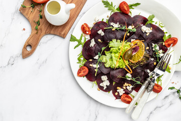 Beet or beetroot salad with greens, cheese, nuts, cranberries on plate with fork, dressing and spices on white background. italian cuisine. banner, menu, recipe place for text, top view