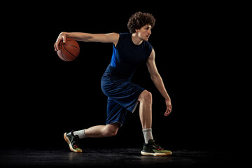 Professional basketball player in action and motion isolated on dark background. Concept of sport,...