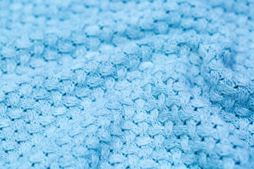 Knitted surface of woolen things as a background. Close-up of soft blue knitted patterns texture. Warm winter clothes. Background textile surface with copy space for text.