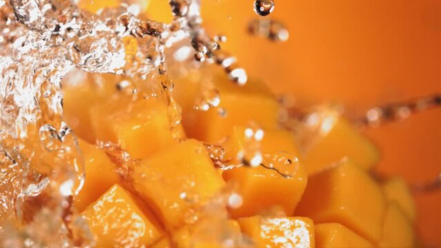 Slow Motion Shot of Water Splashing through Mango Cube Slices