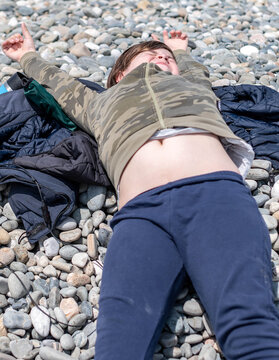the boy is lying on a large pebble with his eyes closed