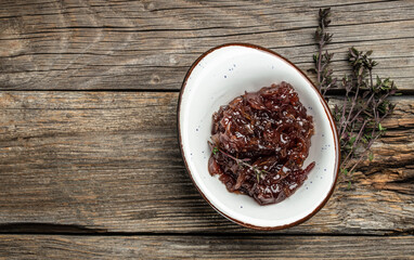 Red onion marmalade jam, confiture, chutney with wine and thyme on a wooden background, Delicious sauce. Gourmet. banner, menu, recipe place for text, top view
