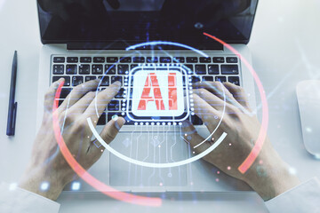 Double exposure of creative artificial Intelligence abbreviation with hand typing on computer...