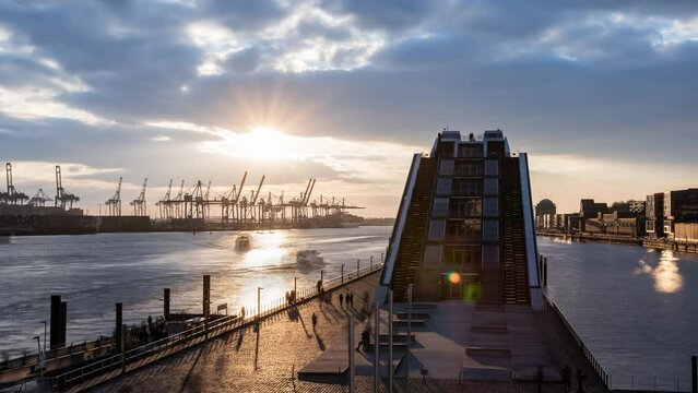 4K Time lapse: Hamburg, Elbe river, Germany: Harbor sunset scenery from Cruise Terminal Altona. View to the office building "Dockland" in the district Altona and the cranes of the container terminal "