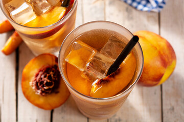 Glass of peach tea with ice cubes on wooden table. Top view
