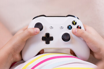 Closeup little girl hands with joystick play video game. © Aleksei