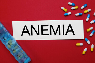 Card with word Anemia and pills on red background, flat lay