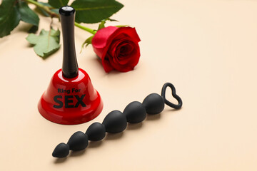 Bell with text Ring For Sex, anal beads and rose on beige background