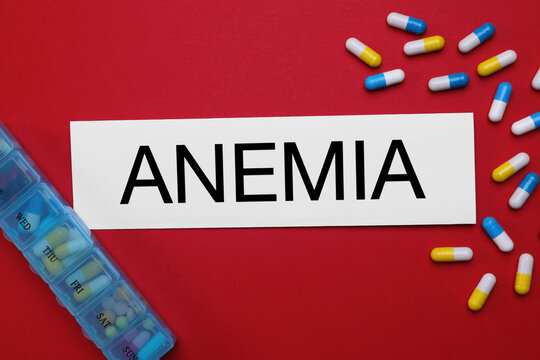 Card with word Anemia and pills on red background, flat lay