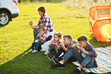 Family spending time together. Four kids with mother eat watermelon outdoor.