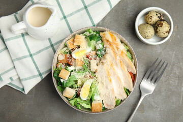 Delicious fresh Caesar salad in bowl on grey table, flat lay