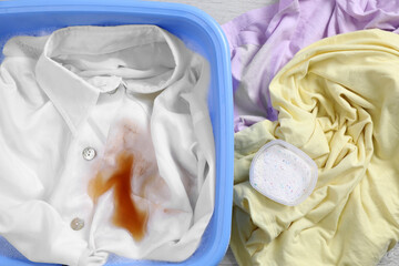 Garment and powdered detergent near basin with white shirt, top view. Hand washing laundry