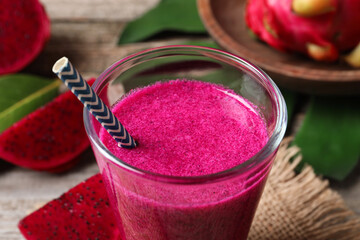 Glass of tasty pitahaya smoothie with straw on table, closeup view