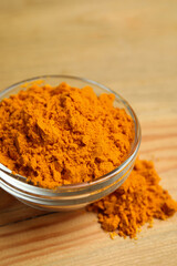 Aromatic saffron powder in bowl on wooden table, closeup