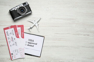 Flat lay composition with passport, toy plane and tickets on white wooden background, space for text. Visa receiving