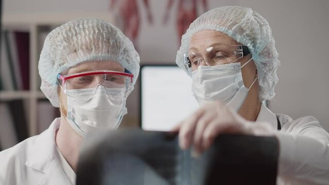Doctors in protective mask and goggles examine x-ray. Realtime