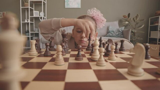 POV slowmo of smart 8 year old girl playing chess with herself at home, thinking out moves and combinations