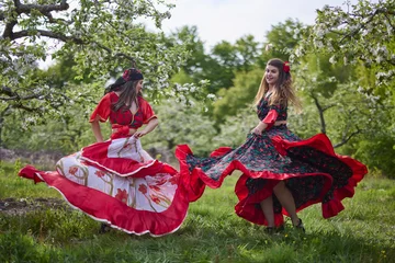 Poster two dancers in traditional gypsy dresses dance in nature on a spring day © czamfir
