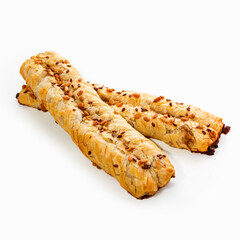 Two crispy appetizing pigtail made of puff pastry with sunflower seeds, close-up. White background