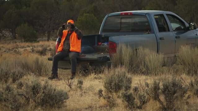 Hunter filming how two men carry a dead deer buck towards the pick up for transportation