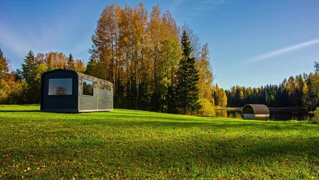 Vivid fall colors in tree foliage around tiny house on lake; time lapse