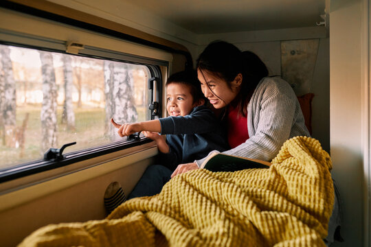 A multicultural mother with her child lies on the bed in the van.