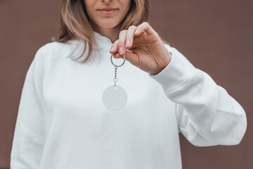 White round keychain mockup in woman's hand. Blank white sublimation keychain. - obrazy, fototapety, plakaty