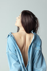 Beautiful shape of female back. One beautiful woman posing in shirt isolated over grey studio background