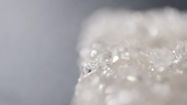 Macro shot of sugar falling down in slow motion. Close up of white sugar crystals. Panoramic shot. Microscopic view