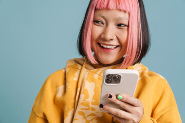Asian girl with pink hair smiling and using mobile phone