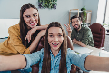 Photo of three business partners take selfie hand demonstrate v-sign meeting workstation indoors
