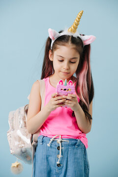 Pretty Tween Girl In Pink Shirt And Unicorn Hair Band Using Her Phone