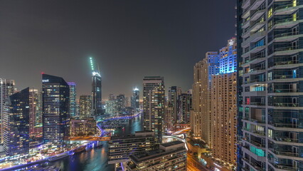 Fototapeta na wymiar Aerial view to Dubai marina skyscrapers around canal with floating boats night timelapse
