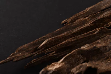 Fotobehang Close UpShot Of Sticks Of oudh On Black Background The Incense Chips Used By Burning It Or For Arabian Oud Oils Or Bakhoor  © mohamed