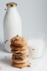 Homemade cookies are sprinkled with chocolate on the background of a bottle of milk and a glass