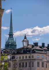 Fototapeta na wymiar Old style lantern on a house with the church Tyska kyrkan and old 1700s house in the background in the old town Gamla Stan a sunny day in Stockholm