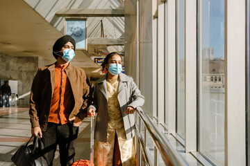 Indian couple wearing face masks standing with bags in airport