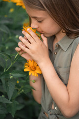 cute beautiful little girl sniffs yellow flowers on the street