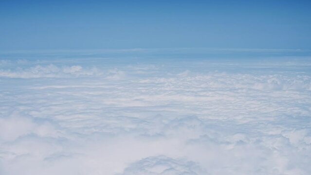 飛行機の窓から眺める空の景色　青空と流れる白い雲　4K　UHD