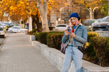 Young woman wearing hat using mobile phone while walking in park