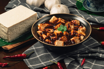 Traditional spicy hot chinese food,Mapo Tofu dressed with tea cup,on wooden plate with dark background.