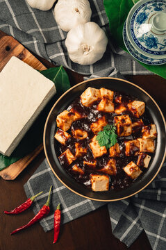 Traditional spicy hot chinese food,Mapo Tofu dressed with tea cup,on wooden plate with dark background.
