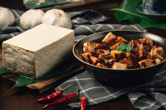 Traditional spicy hot chinese food,Mapo Tofu dressed with tea cup,on wooden plate with dark background.