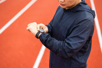 Young man wearing sportswear blue jacket using Smart Watch Showing Heart Rate Monitor. Technology for health and sport mode. Exercise and take statistics to develop your potential.