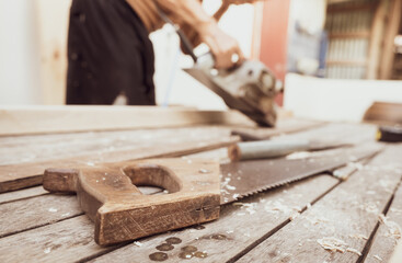 Hand saw with a wooden handle on blur carpenter working with electric wood planer. Carpenter tools....