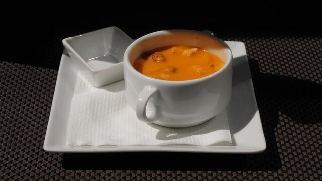 Woman eating Gazpacho soup, closeup shot, only bowl and moving spoon in frame. Popular Spanish meal served at outdoor terrace of typical cafe