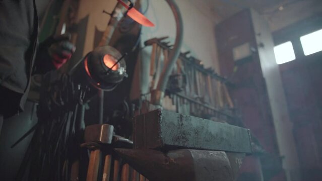 Blacksmith taking out hot knife from the forge and hardening steel in an oil. Damascus steel knife.