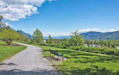 Fototapeta premium Riverbank walkway with overview of snow caps on Rocky mountains