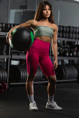 Fototapeta na wymiar Sports woman stands with a ball in the gym.